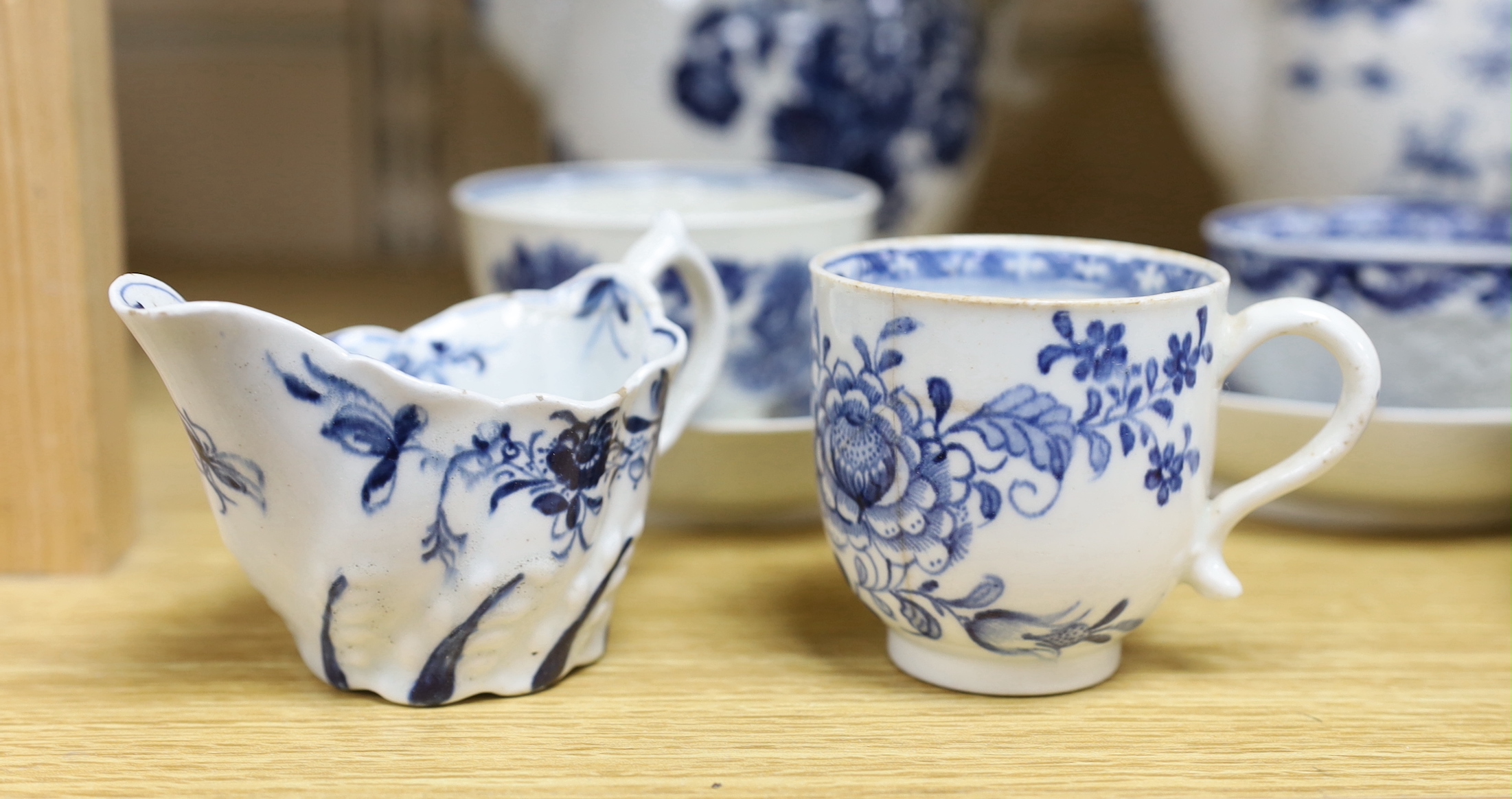 A collection of 18th century Worcester and Lowestoft blue and white tea and coffee wares, including a Lowestoft long fence pattern teapot and cover and a similar tea bowl and saucer